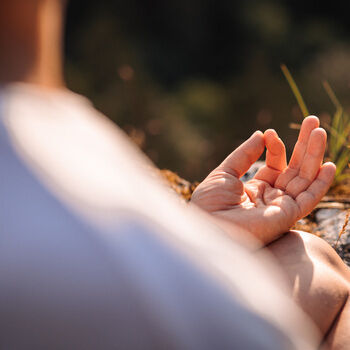 Eine Nahaufnahme einer Hand, die ein Yogazeichen macht.